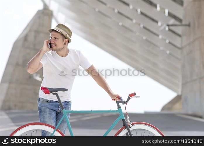 Young handsome guy with a bicycle holding a mobile phone in his hand
