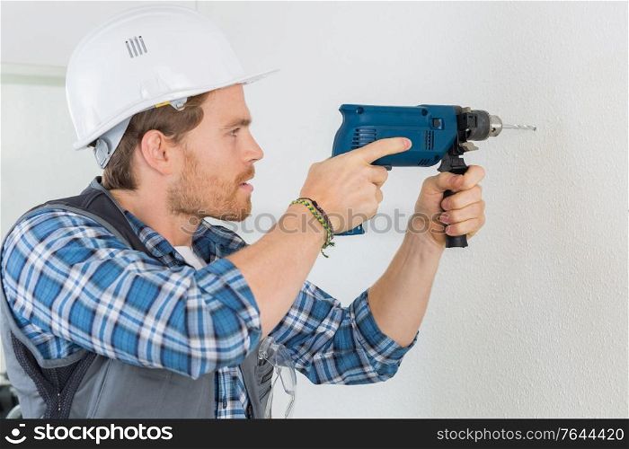 young handsome handyman using a drill at work
