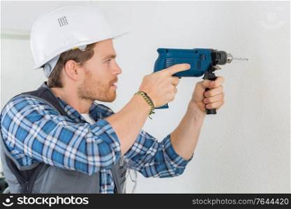 young handsome handyman using a drill at work