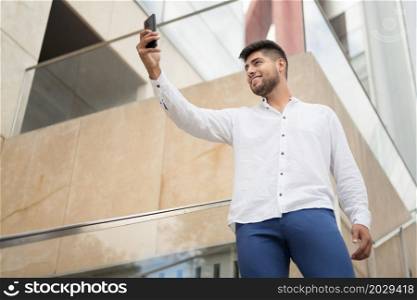 Young handsome hispanic man taking selfie with smartphone outdoors. High quality photo. Young handsome hispanic man taking selfie with smartphone outdoors.