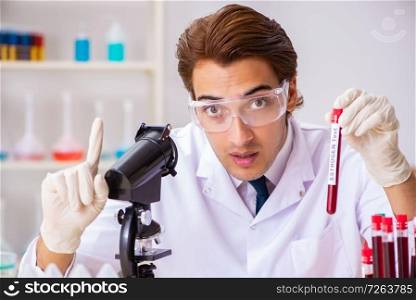 Young handsome lab assistant testing blood s&les in hospital . The young handsome lab assistant testing blood s&les in hospital 