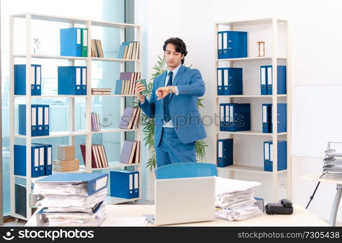 Young handsome male employee with too much work in the office  