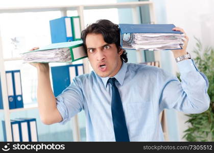 Young handsome male employee with too much work in the office  