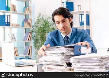 Young handsome male employee with too much work in the office  