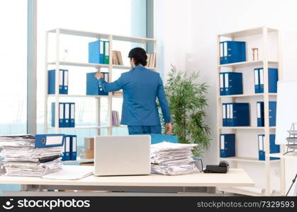 Young handsome male employee with too much work in the office  