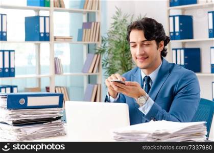 Young handsome male employee with too much work in the office  