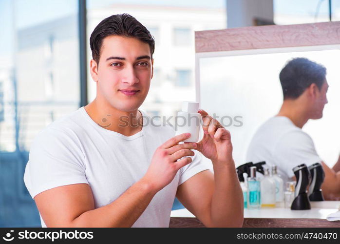 Young handsome man applying face cream