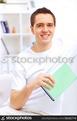 Young handsome man at home with a book