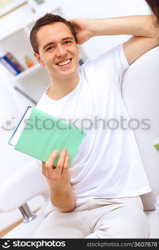 Young handsome man at home with a book