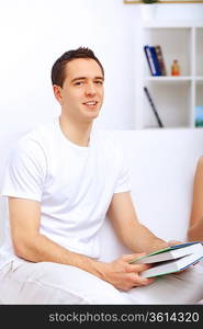 Young handsome man at home with a book