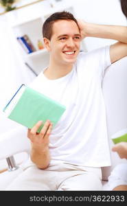 Young handsome man at home with a book