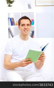 Young handsome man at home with a book