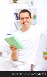 Young handsome man at home with a book