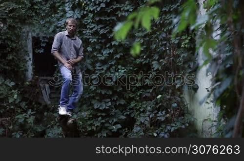 Young handsome man balancing on a dead tree and triyng to make dancing moves