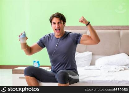 Young handsome man doing morning exercises in the hotel room
