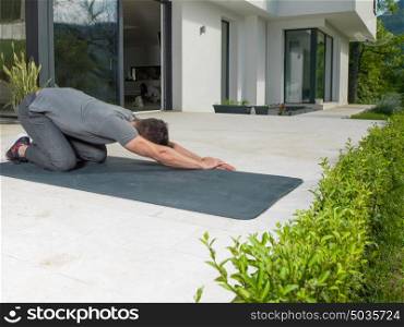young handsome man doing morning yoga exercises in front of his luxury home villa