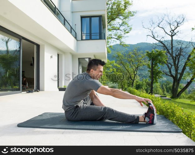 young handsome man doing morning yoga exercises in front of his luxury home villa