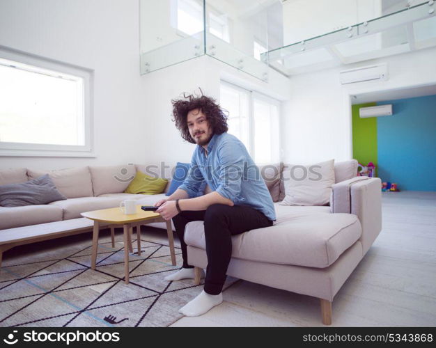 young handsome man enjoying free time watching television in his luxury home villa