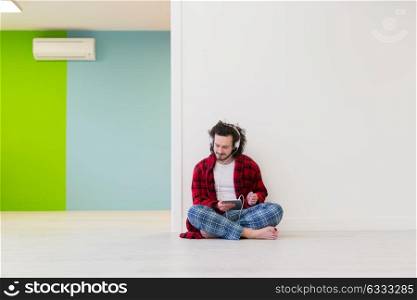 Young handsome man enjoying music through headphones,sitting on the floor at home