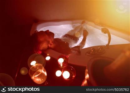 young handsome man enjoys relaxing in the jacuzzi with candles and champagne at luxury resort spa