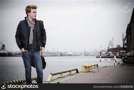Young handsome man fashion model casual style with bag on street urban industrial background