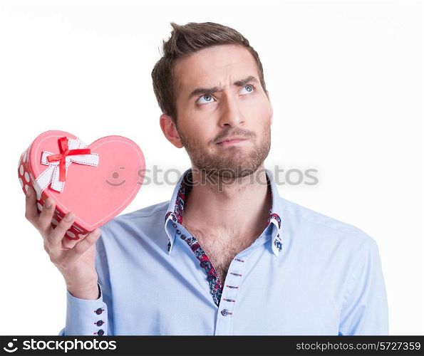 Young handsome man holding a gift and thinking - isolated on white.