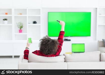 young handsome man in bathrobe enjoying free time watching television in his luxury home