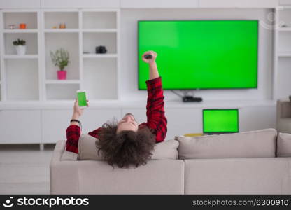 young handsome man in bathrobe enjoying free time watching television in his luxury home