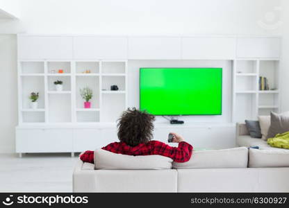 young handsome man in bathrobe enjoying free time watching television in his luxury home