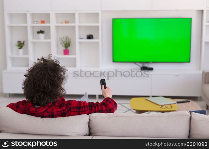 young handsome man in bathrobe enjoying free time watching television in his luxury home