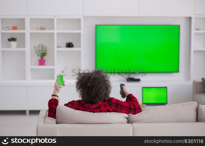 young handsome man in bathrobe enjoying free time watching television in his luxury home