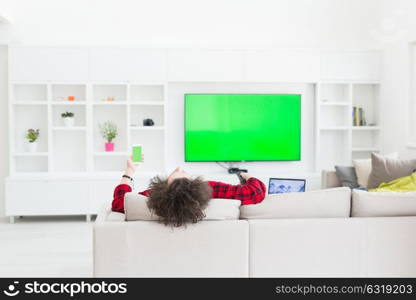 young handsome man in bathrobe enjoying free time watching television in his luxury home