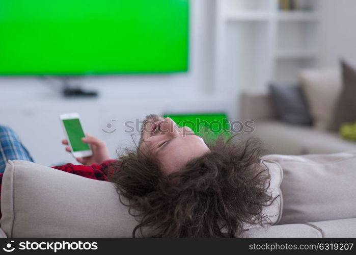 young handsome man in bathrobe enjoying free time watching television in his luxury home