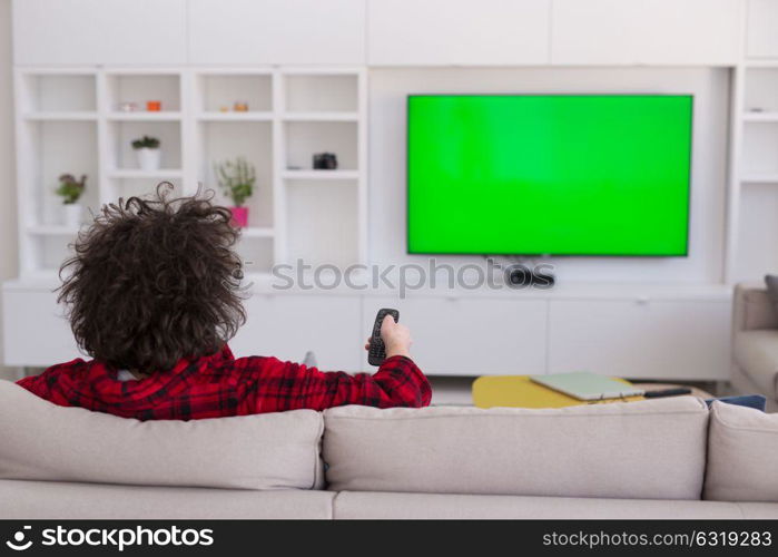 young handsome man in bathrobe enjoying free time watching television in his luxury home