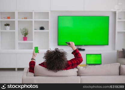 young handsome man in bathrobe enjoying free time watching television in his luxury home