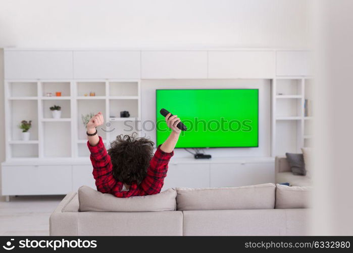 young handsome man in bathrobe enjoying free time watching television in his luxury home