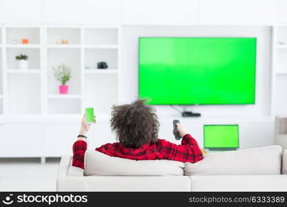 young handsome man in bathrobe enjoying free time watching television in his luxury home