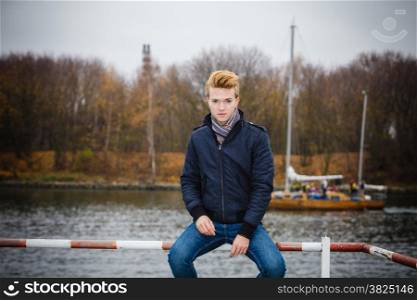 Young handsome man in full length fashion model casual style hair styling outdoor against a marine harbour