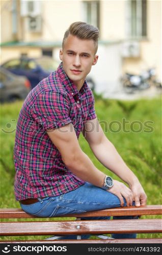 Young handsome man in plaid shirt on the background of summer street