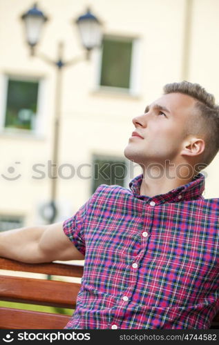 Young handsome man in plaid shirt on the background of summer street