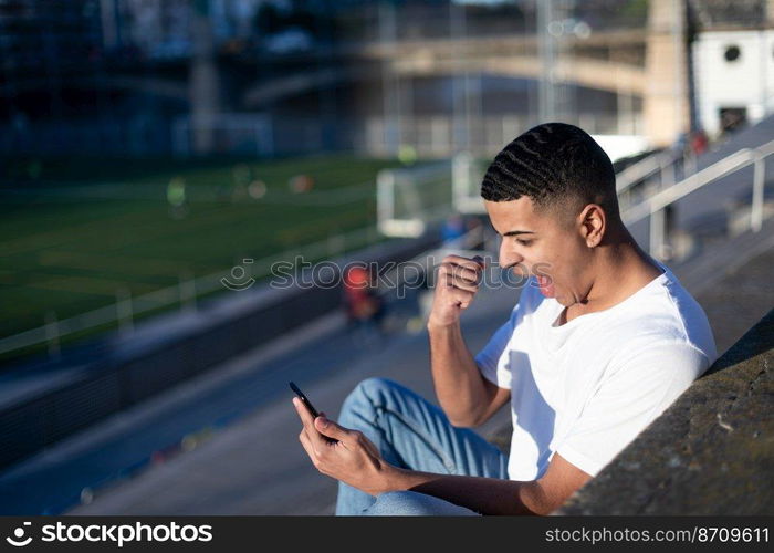 Young handsome man in t-shirt and jeans on a stadium bleachers alone