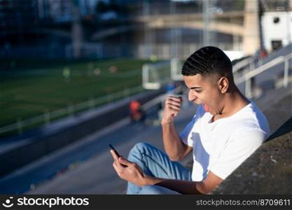 Young handsome man in t-shirt and jeans on a stadium bleachers alone