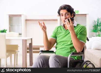 Young handsome man in wheelchair at home 