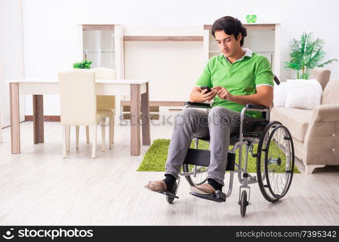 Young handsome man in wheelchair at home 