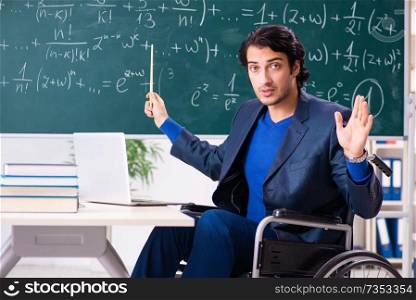 Young handsome man in wheelchair in front of chalkboard 
