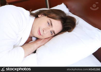 young handsome man lying in a bed at home