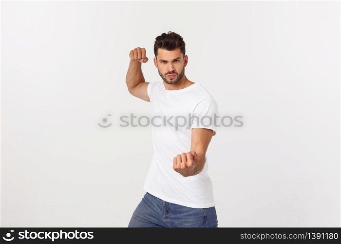 Young handsome man over isolated background Punching fist to fight, aggressive and angry attack, threat and violence.. Young handsome man over isolated background Punching fist to fight, aggressive and angry attack, threat and violence