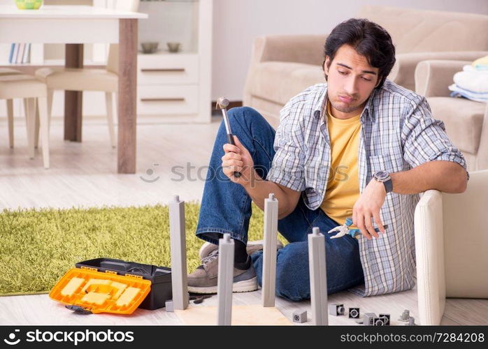 Young handsome man repairing chair at home 