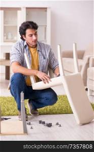 Young handsome man repairing chair at home 