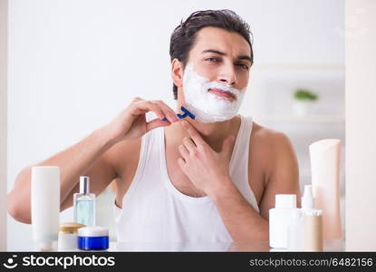 Young handsome man shaving early in the morning at home